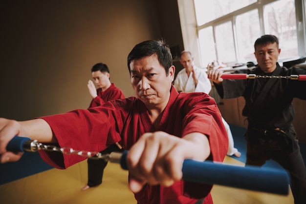 Photo fighters in different colors keikogi training with nunchuck.