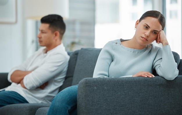 fighting ignore and couple with stress divorce and depression with tension in living room apartment house and man with woman on couch frustrated and angry with emotions and conflict in lounge