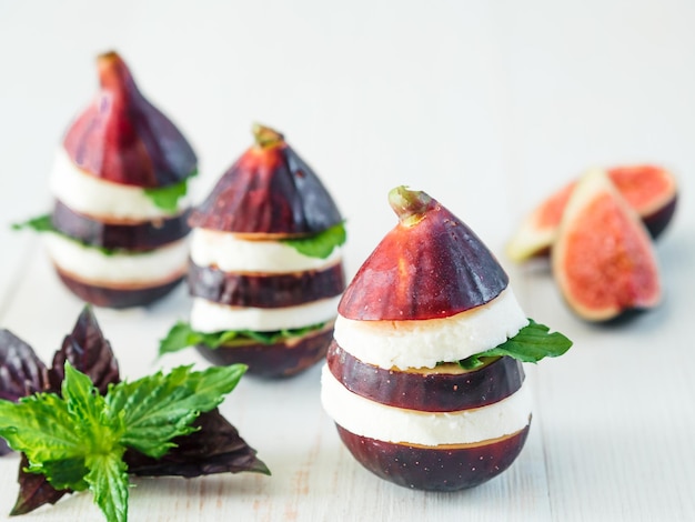 Figs and cheese appetiezer with basil and mint leaves