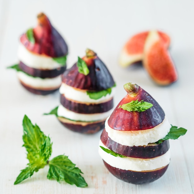 Figs and cheese appetiezer with basil and mint leaves