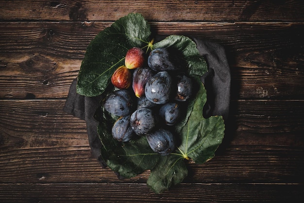 Figs in fig leaves on wooden table top view