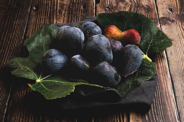 Figs in fig leaves on wooden table top view