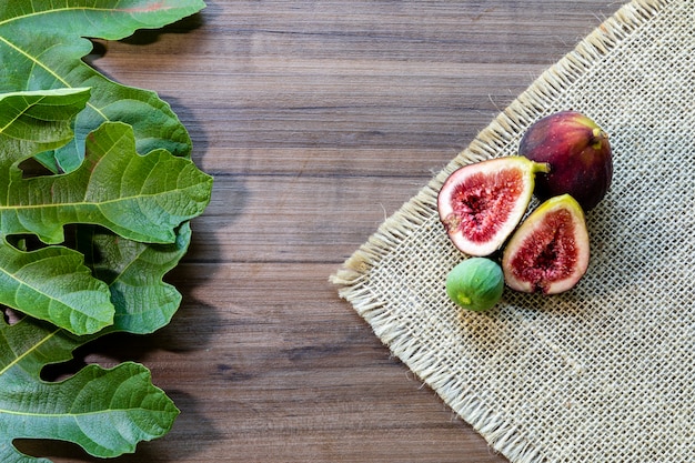 Figs, green leaves on rustic wooden background