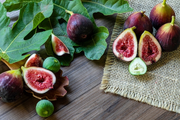 Figs, green leaves on rustic wooden table