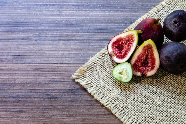 Photo figs, green leaves on rustic wooden table