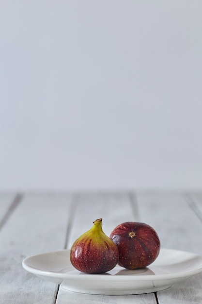 Figs on a plate on white wooden table