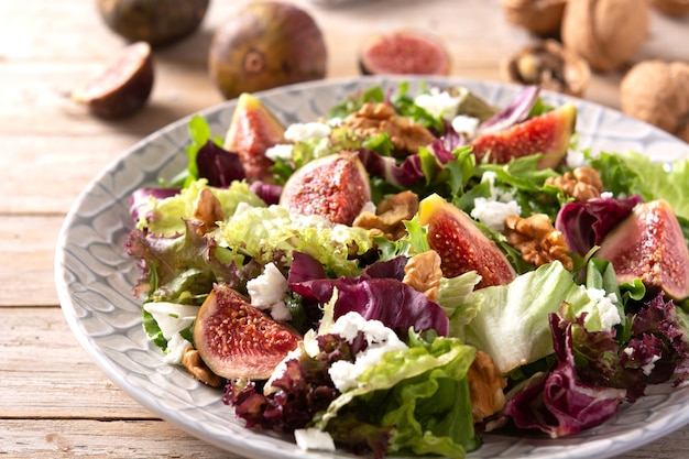 Figs salad with cheese and walnuts on wooden table