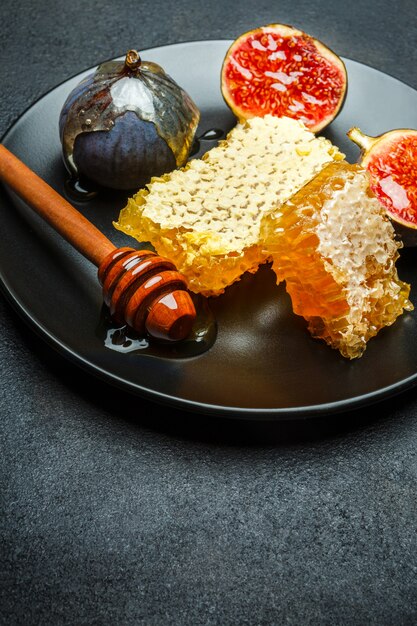 暗いコンクリートテーブルの上の皿の上に蜂蜜とイチジク