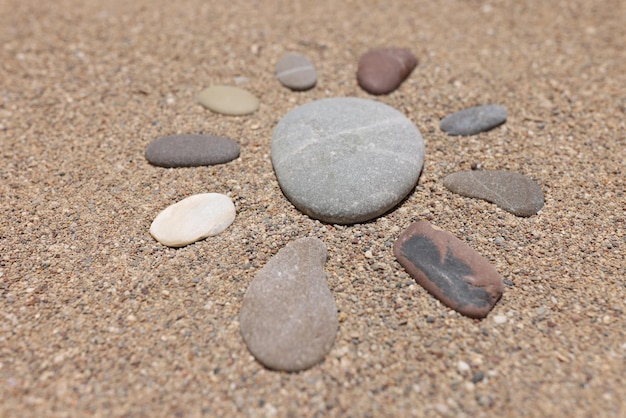 태양의 그림은 여름에 모래 해변에 자갈 돌로 만들어집니다