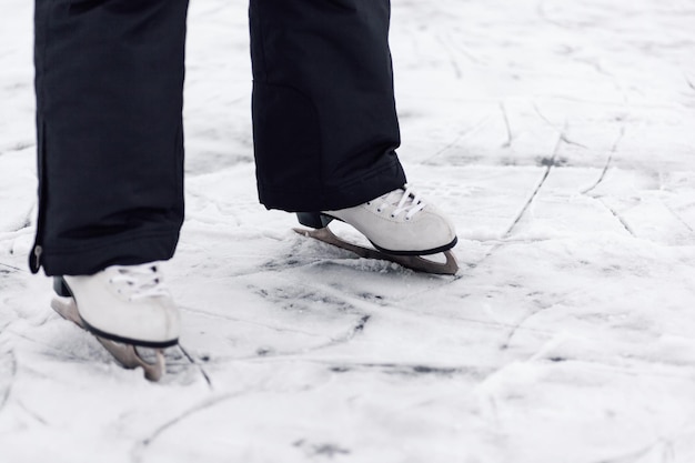 Figure skating skates closeup of mans legs in black winter\
pants standing on ice of frozen lake in w...