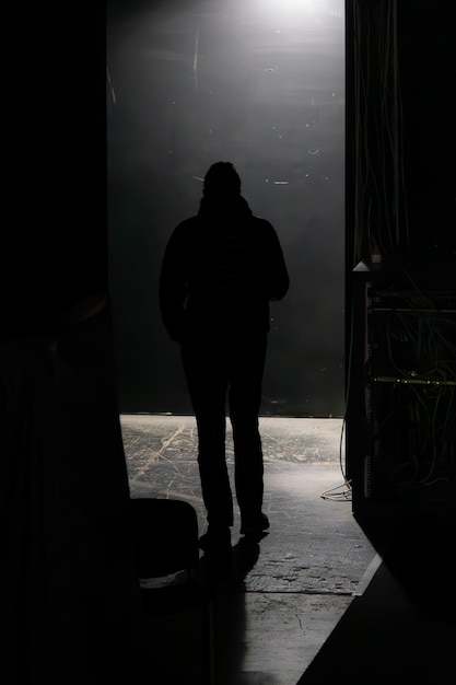 Photo figure of a stranger go away from the camera man in the dark exit to the stage