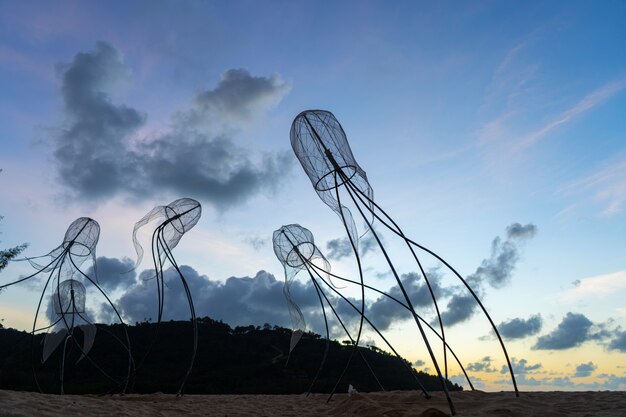 Figures of jellyfish on a background of a sunset sky.