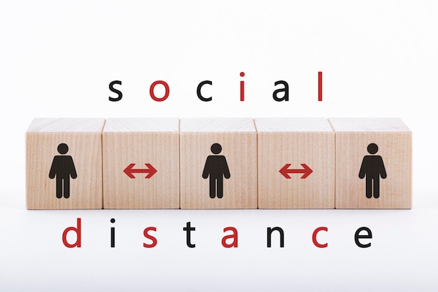 Figures of people on wooden blocks depicted in the distance The concept of social distance