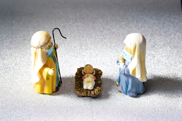 Figures of Saint Joseph, the Virgin Mary and the newborn baby Jesus with hygienic masks.