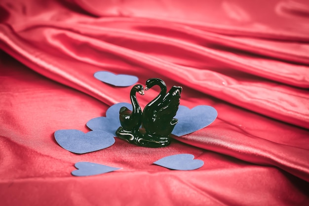 Figures of two black swans on a red background