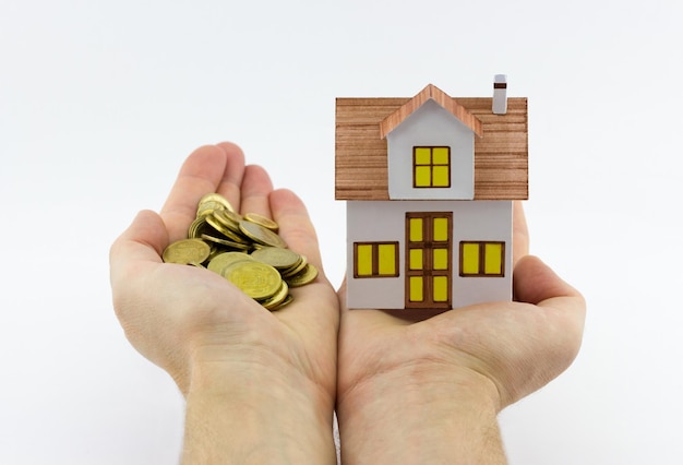 Figurine of a house and coins in male hands