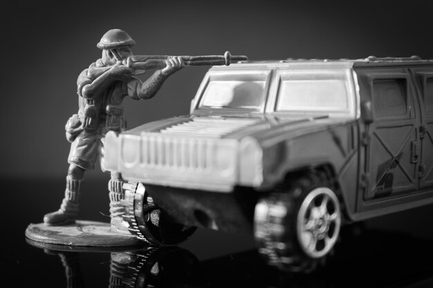 Photo figurine shooting with rifle by car over black background