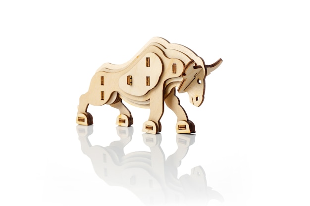 Figurine of a toy wooden bull on a white background with reflection.