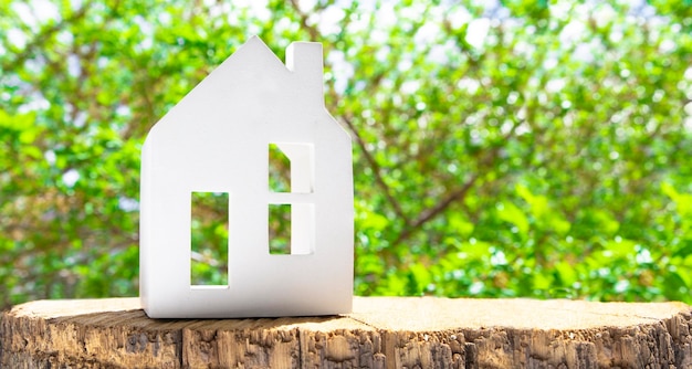 Figurine of a white ceramic house standing on a wooden surface with green trees