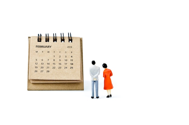 Figurines by calendar against white background