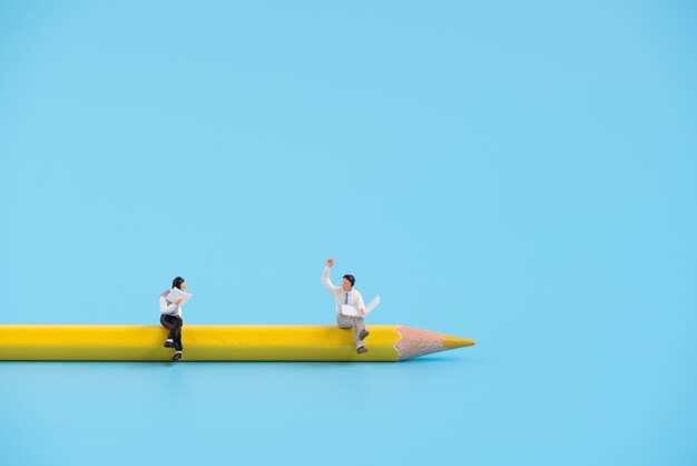 Figurines on pencil against blue background