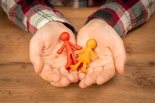 Figurines of young family without child in human hands Concept of family values photo