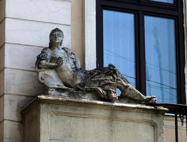 Figuur van een meisje dat op vakantie ligt Steen standbeeld op het oude gebouw