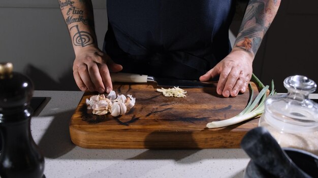 Foto fijn gehakte knoflook ligt op een snijplank voor de kok in de keuken