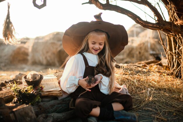 Fijne Halloween. Een schattig meisje in een heksenkostuum is in het hol van de heks. Leuke vrolijke kleine heks brouwt een toverdrank. Halloween.