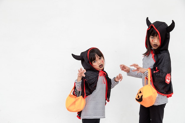 Foto fijne halloween! twee kinderen in halloween-kostuums en met pompoenen op witte achtergrond