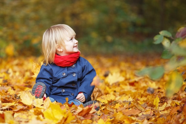 Fijne herfst Klein lief meisje speelt met bladeren in een herfstpark Kopieer de ruimte vallende bladeren