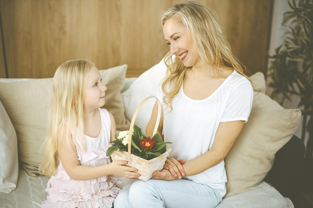 Fijne Moederdag. Kinddochter feliciteert moeder en geeft haar mand met lentebloemen en ansichtkaart met harttekening. Familie- en jeugdconcepten