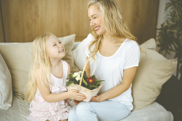 Fijne Moederdag. Kinddochter feliciteert moeder en geeft haar mand met lentebloemen en ansichtkaart met harttekening. Familie- en jeugdconcepten