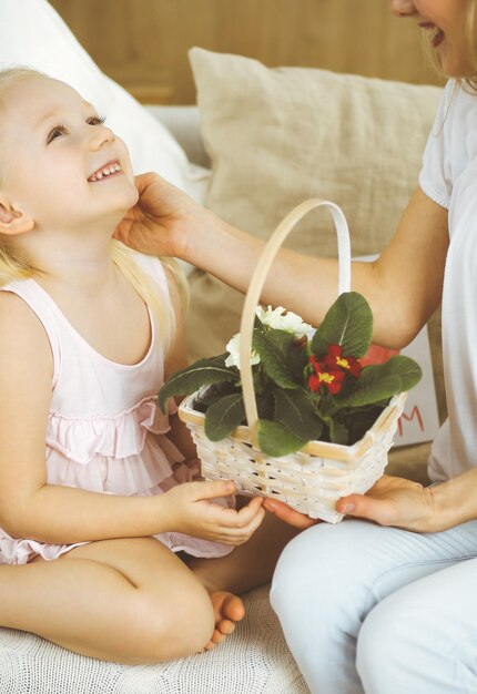 Fijne moederdag. kinddochter feliciteert moeder en geeft haar mand met lentebloemen en ansichtkaart met harttekening. familie en kindertijd concepten.