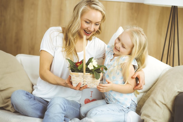 Fijne Moederdag. Kinddochter feliciteert moeder en geeft haar mand met lentebloemen. Familie en kindertijd concepten.