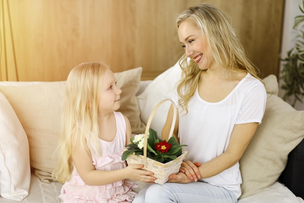 Fijne Moederdag. Kinddochter feliciteert moeder en geeft haar mand met lentebloemen. Familieconcept.