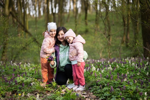 Fijne Moederdag We houden van je moeder Moeder met een boeket bloemen en twee dochters in het lentebloeiende bos