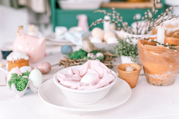 Fijne paas- en lentevakantie tijd feestelijk tafellandschap decor traditioneel diner eten paaseieren en gebakken taarten op tafel thuis konijn en wilg bleke pop pastel blauwe en roze kleur