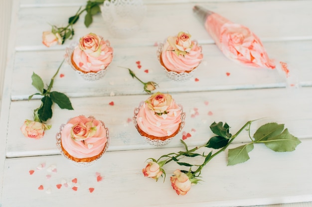 Fijne smakelijke muffins met een roze crème versierd met echte ros