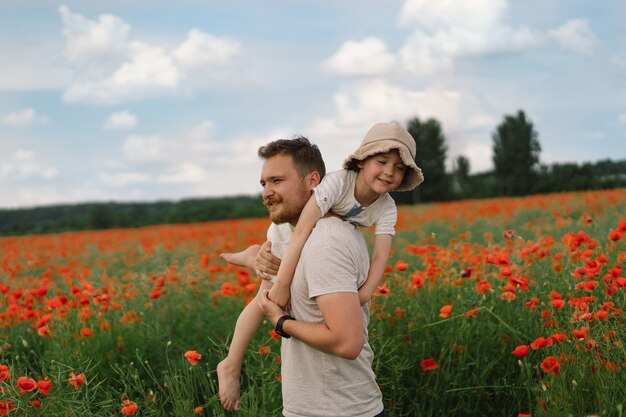 Fijne vaderdag kleine jongen en vader spelen in een prachtig veld met rode klaprozen