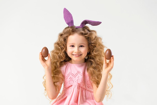 Foto fijne vakantie pasen kinderen meisje in konijn haas konijnenoren en chocolade-eieren