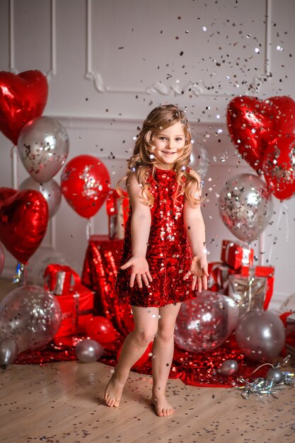 Fijne Valentijnsdag! schattig meisje in een rode jurk met ballonnen en confetti