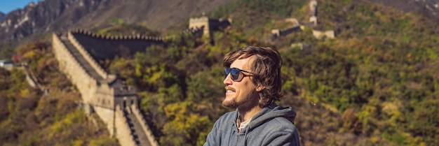Fijne vrolijke vrolijke toeristenman bij de grote muur van china die plezier heeft op reizen, lacht, lacht en