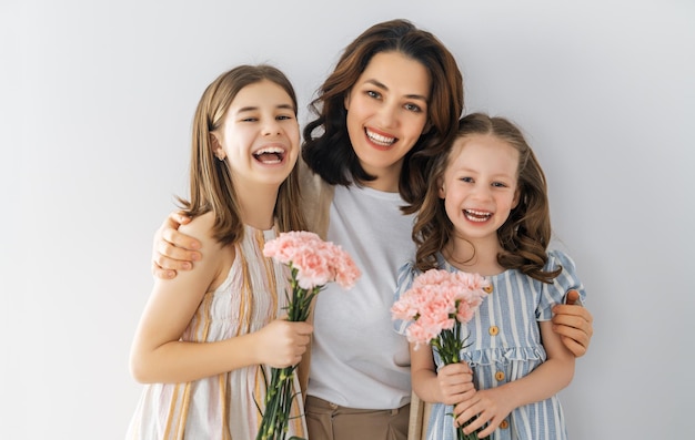 Fijne vrouwendag Kinderen feliciteren moeder en geven haar roze bloemen Moeder en meisjes glimlachen