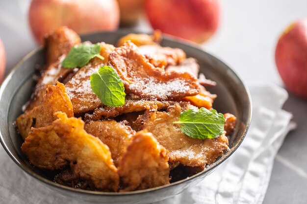 Fijngebakken appelpannenkoekjes bestrooid met vanillesuiker en kaneel gegarneerd met muntblaadjes.