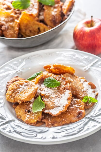 Fijngebakken appelpannenkoekjes bestrooid met vanillesuiker en kaneel gegarneerd met muntblaadjes.