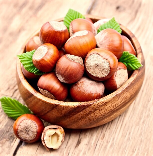 Filbert nuts with leaf on wooden table .