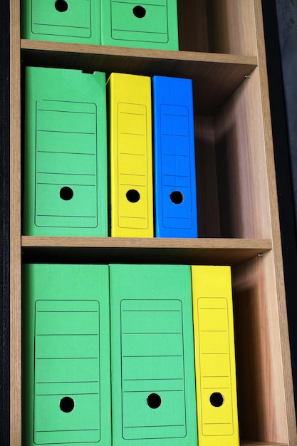 File folders for storing documents are on a wooden shelf in the office