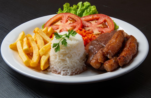 Filet met friet geserveerd met rijst en sla tomaat en wortelsalade