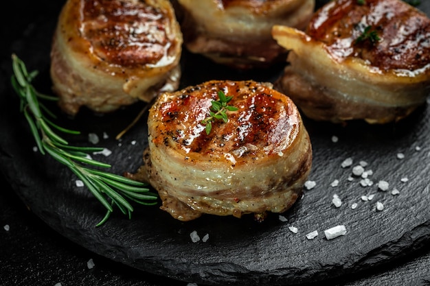 Filet mignon served on a stone board. portion of juicy beef tenderloin steak covered bacon. banner, menu recipe top view.